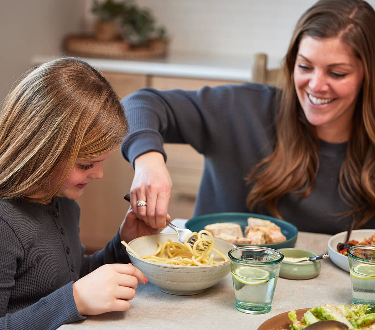 mother with daughter eating pasta